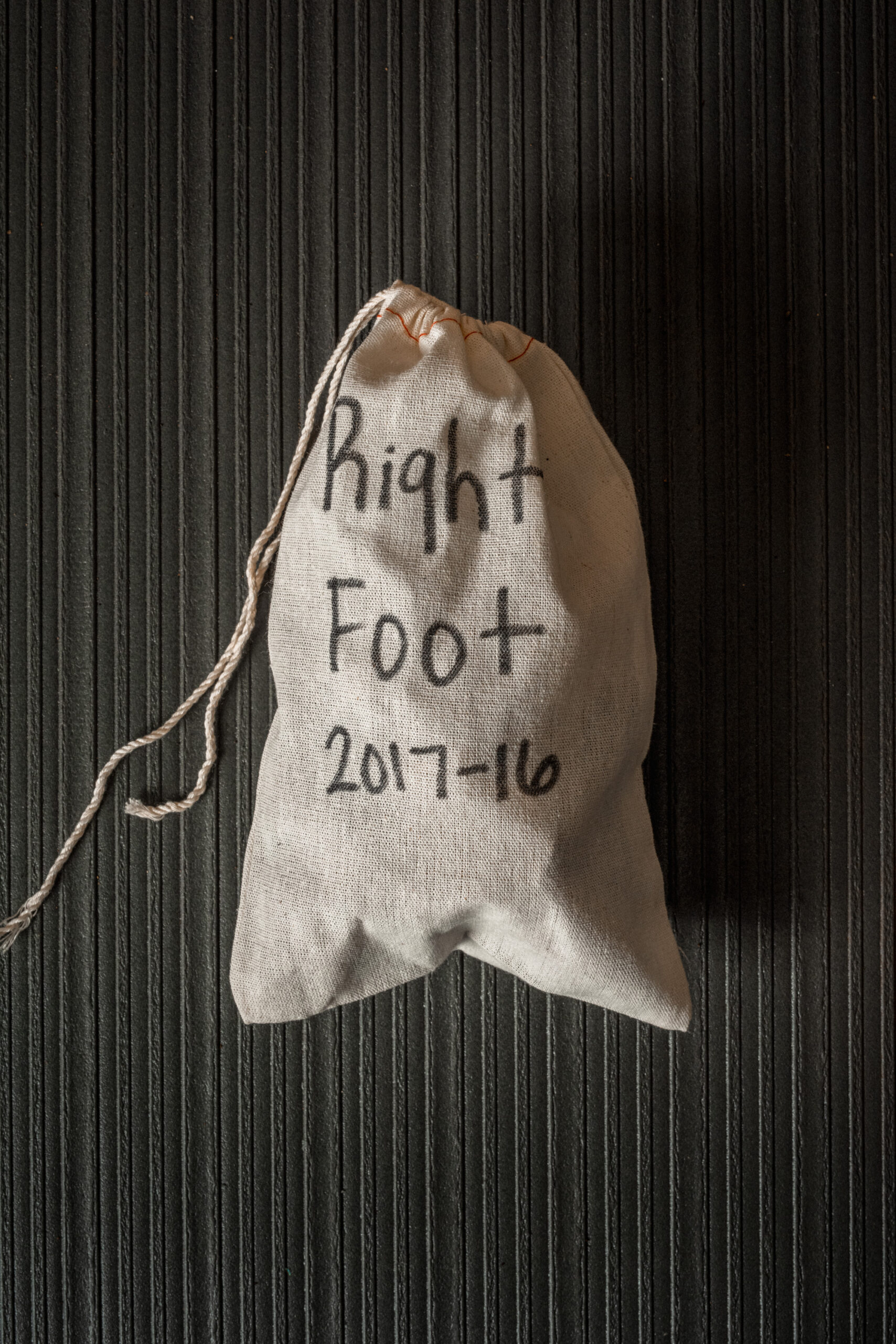 overhead view of a pouch with the words "Right Foot 2017-16" handwritten on the fabric in marker