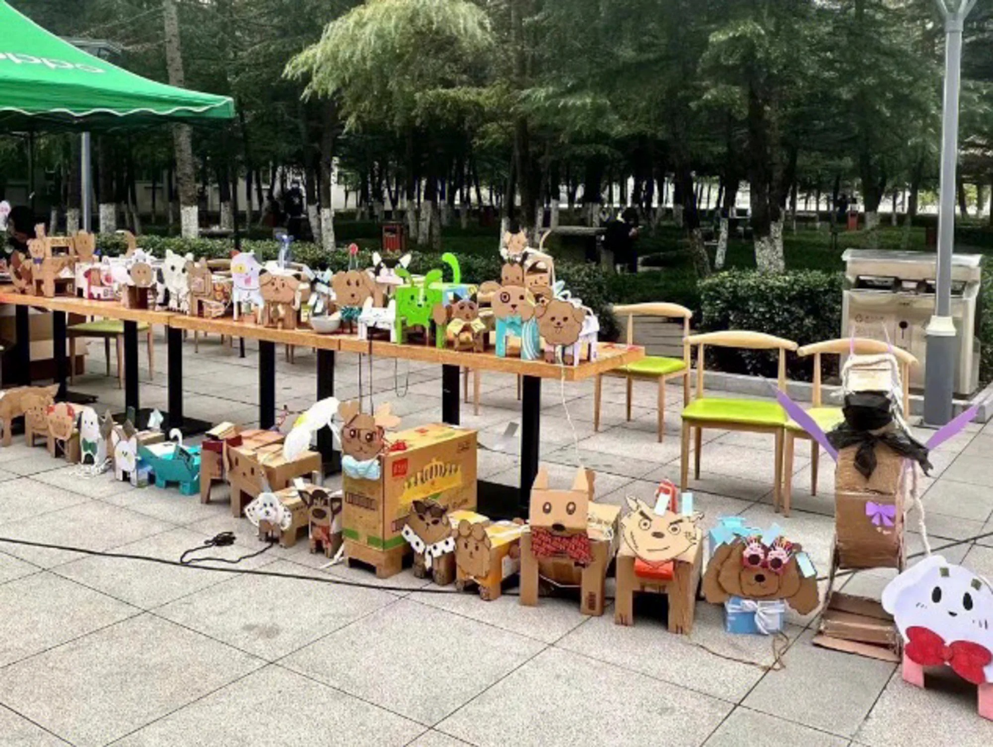 A photo of dozens of cardboard dogs lined up on the table or on the ground.