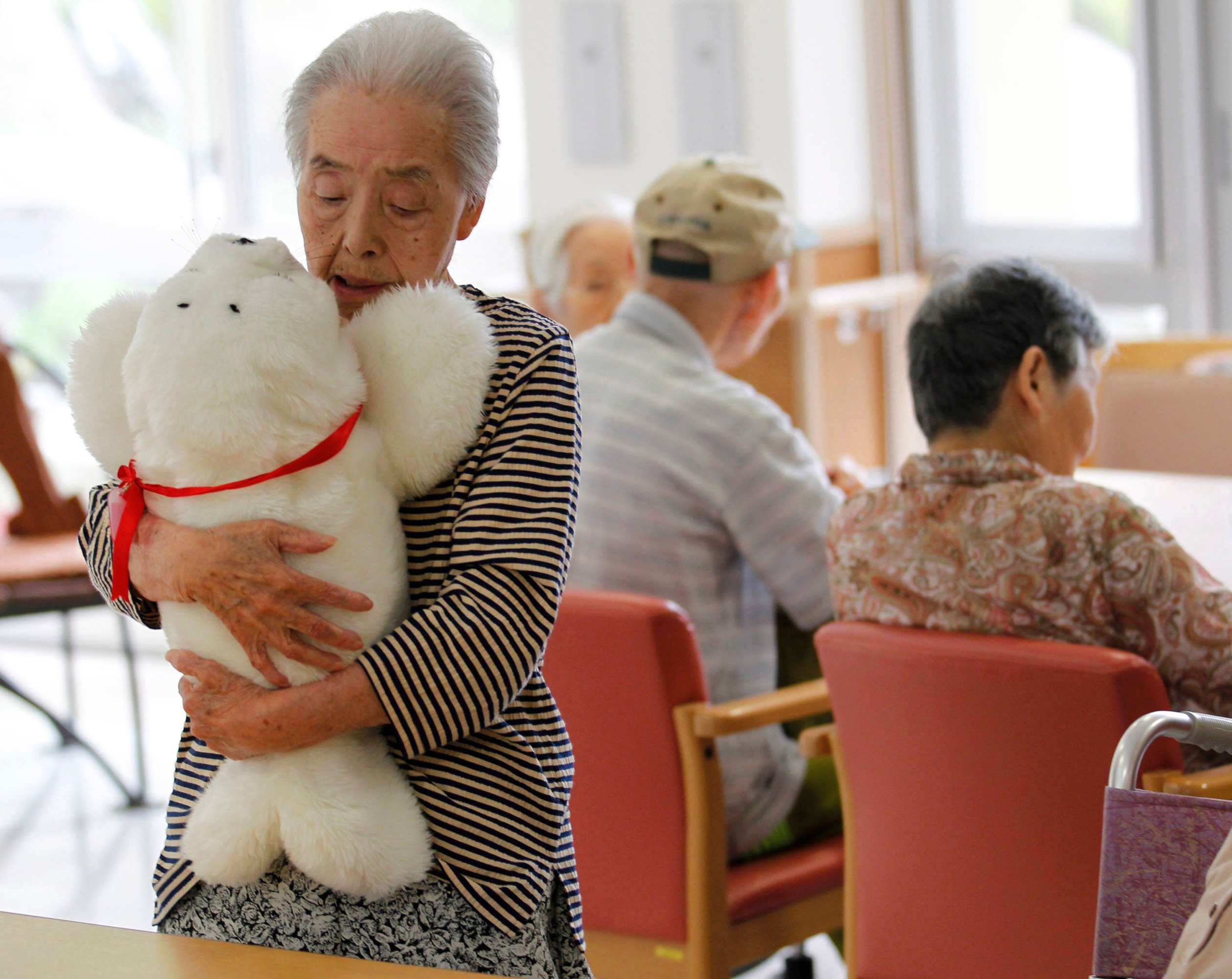 Satsuko Yatsuzaka (84) holds a therapeutic robot named Paro at the Suisyoen retirement home.