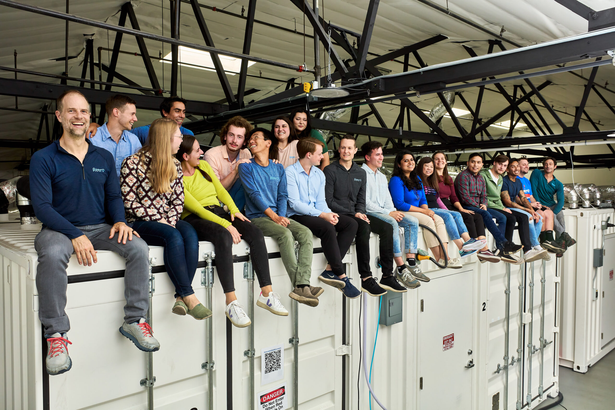 Retro Bio employees sitting on the top of the shipping containers that make up their lab space