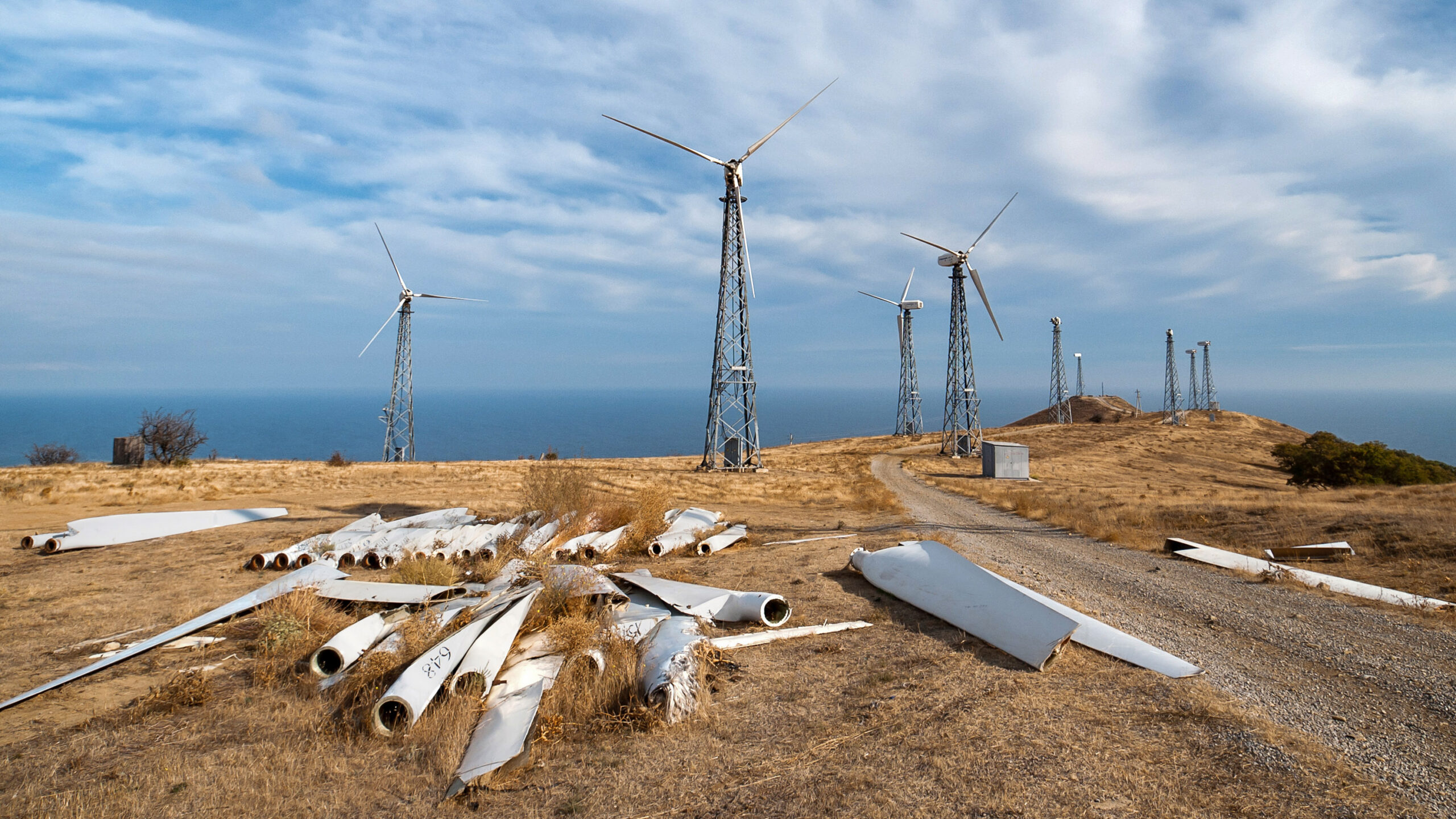 Dilapidated wind power station with spare parts of wind turbines in the foreground