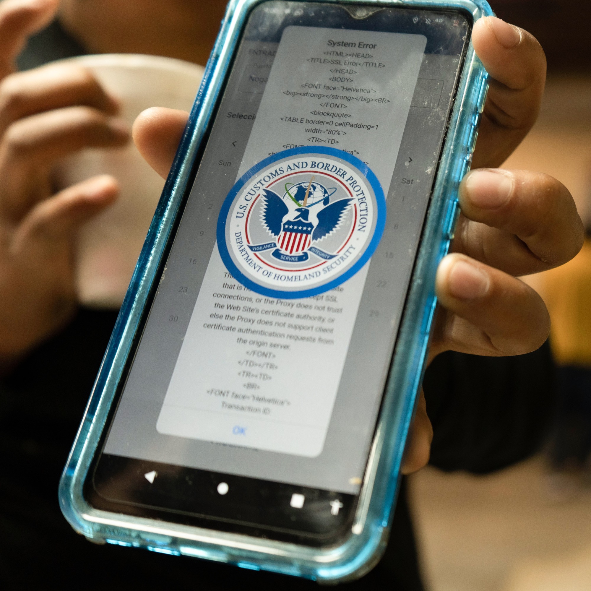 close up of a phone with the US Customs and Border Protection logo visible on the screen over a system error code