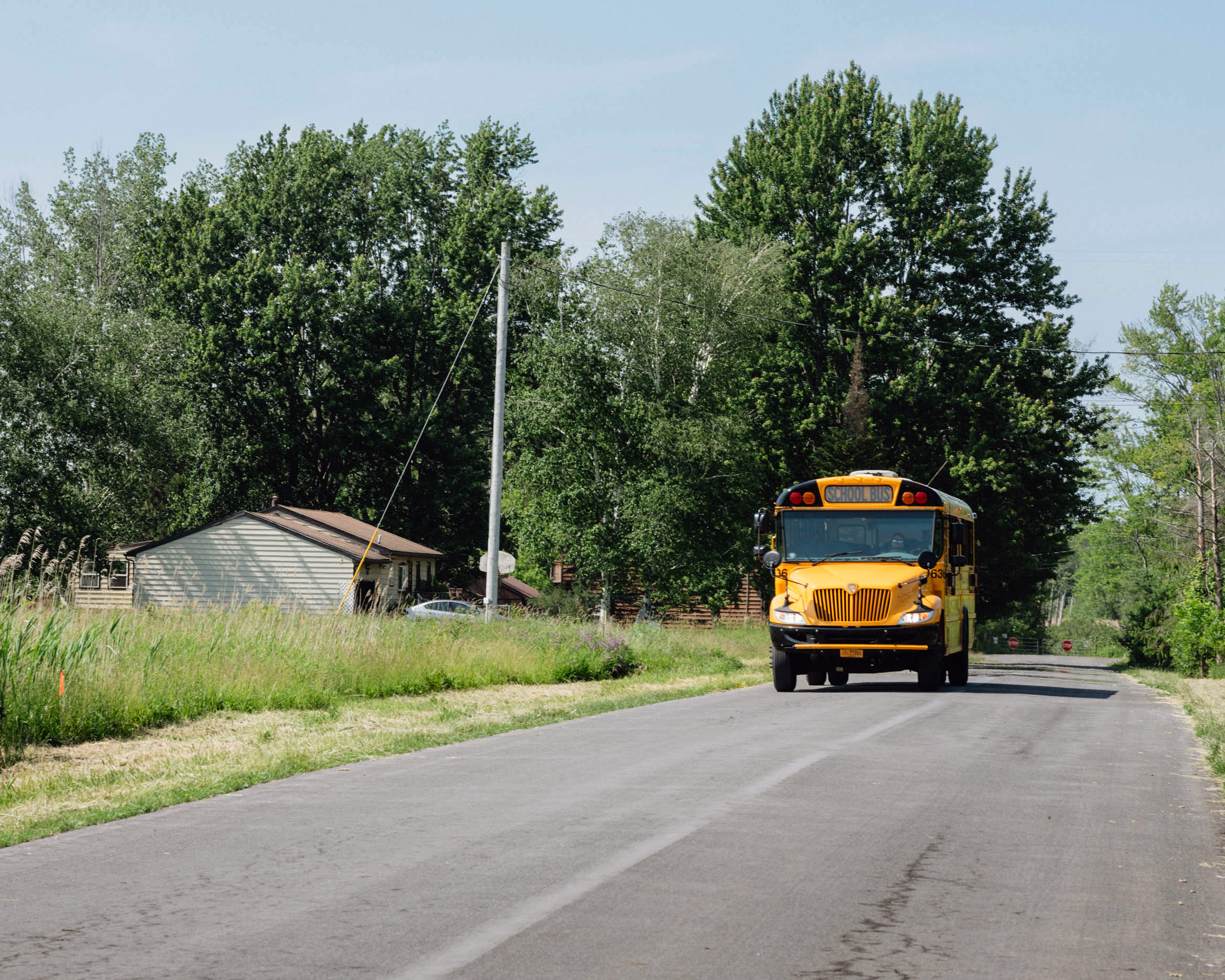 A school bus drives down a rural street in New York.