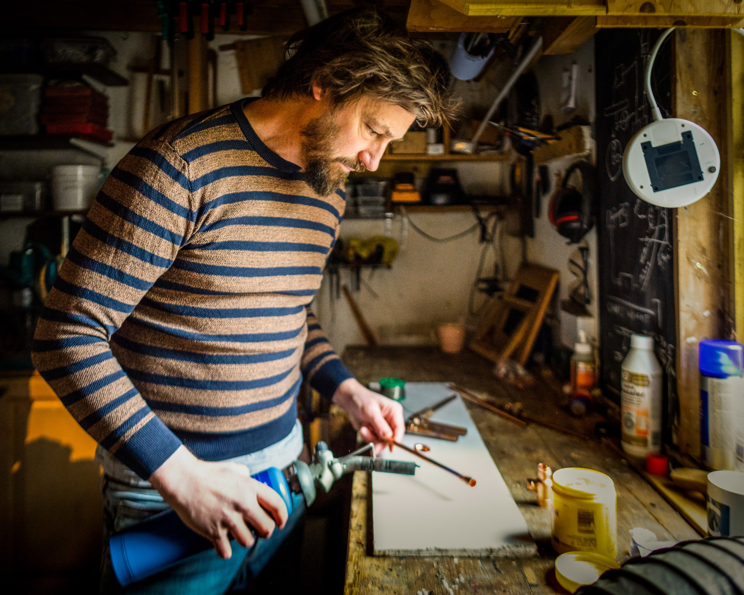 Chris holding a blowtorch at a workbench
