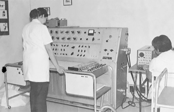 photo from the 1970s of two medical professionals facing an eeg machine