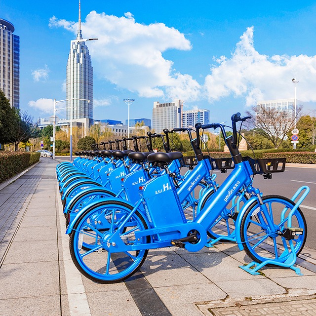 a row of blue Yuoun hydrogen bikes for rent in the city