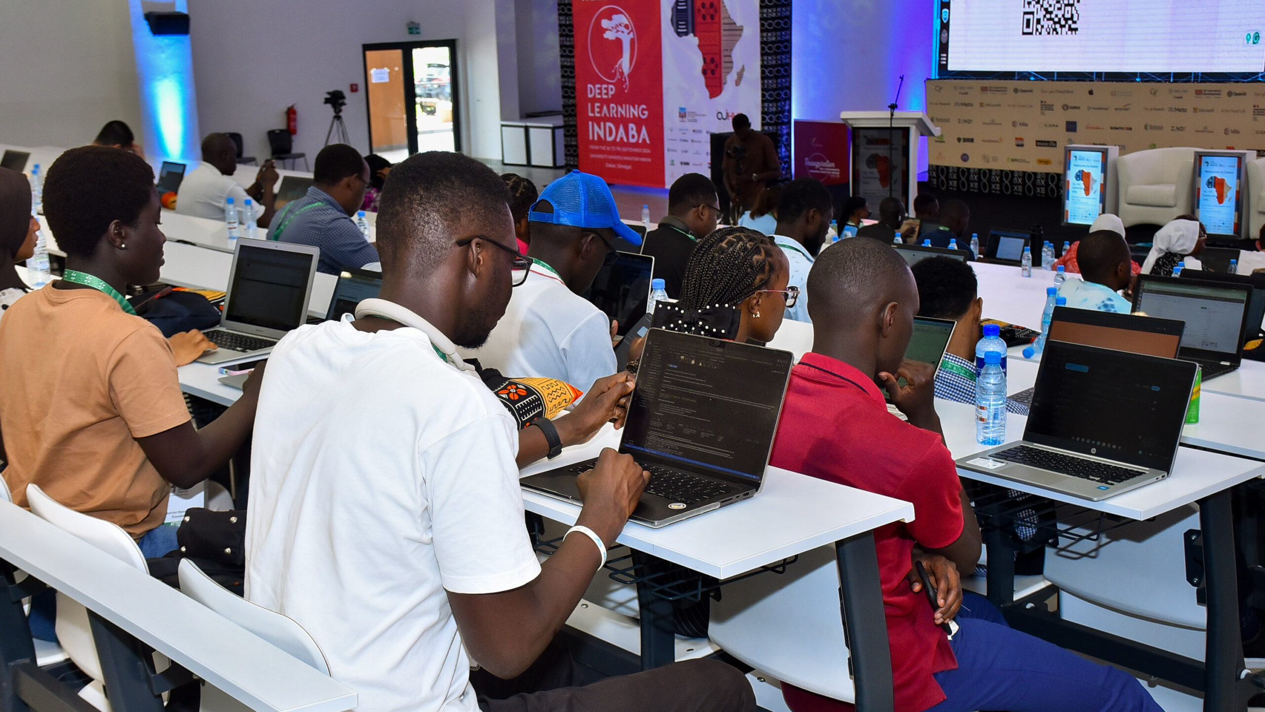 Attendees of Deep Learning Indaba 2024 in session hall on their computers