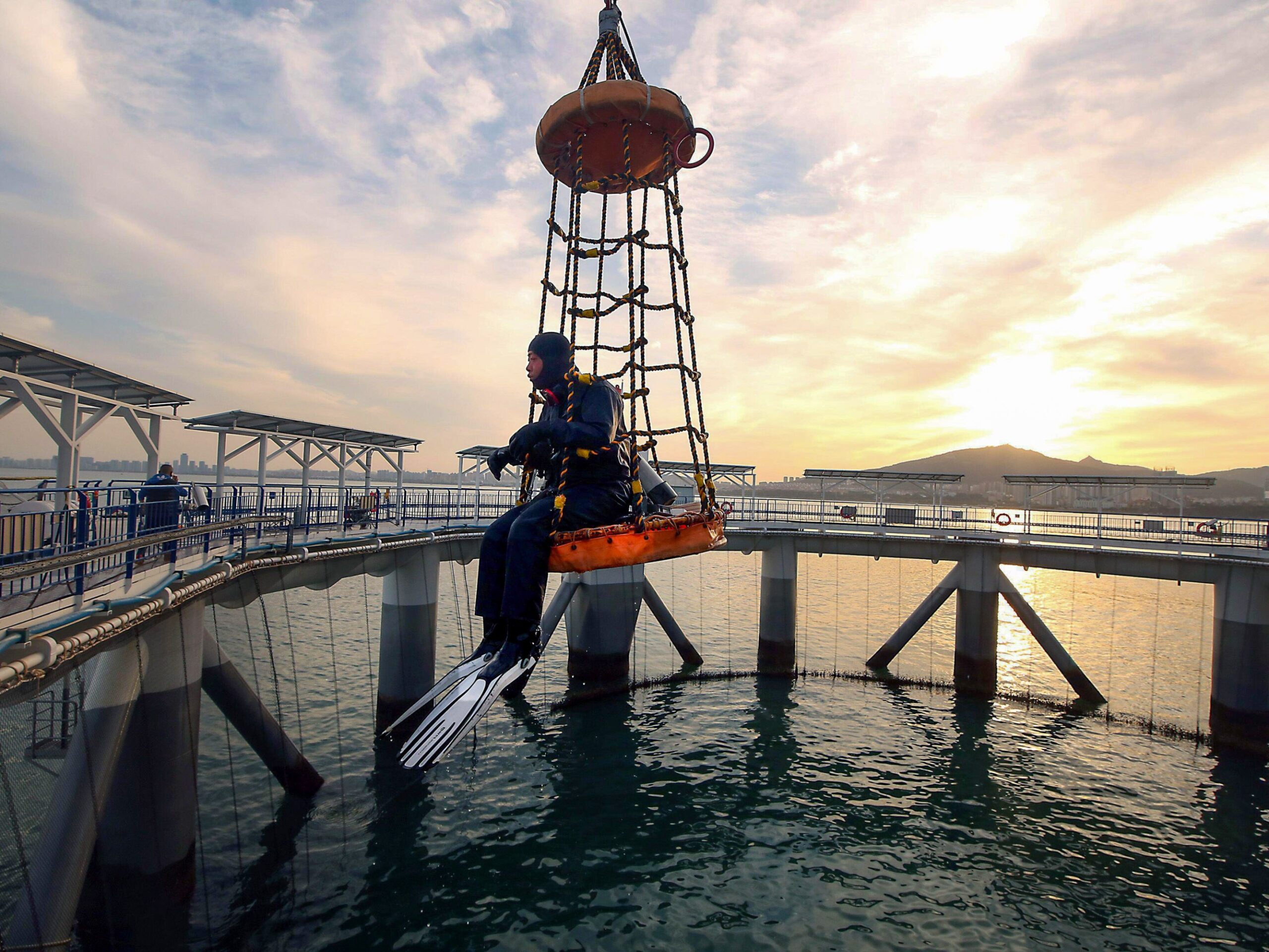 a person in a wetsuit at sunset sitting in a net 