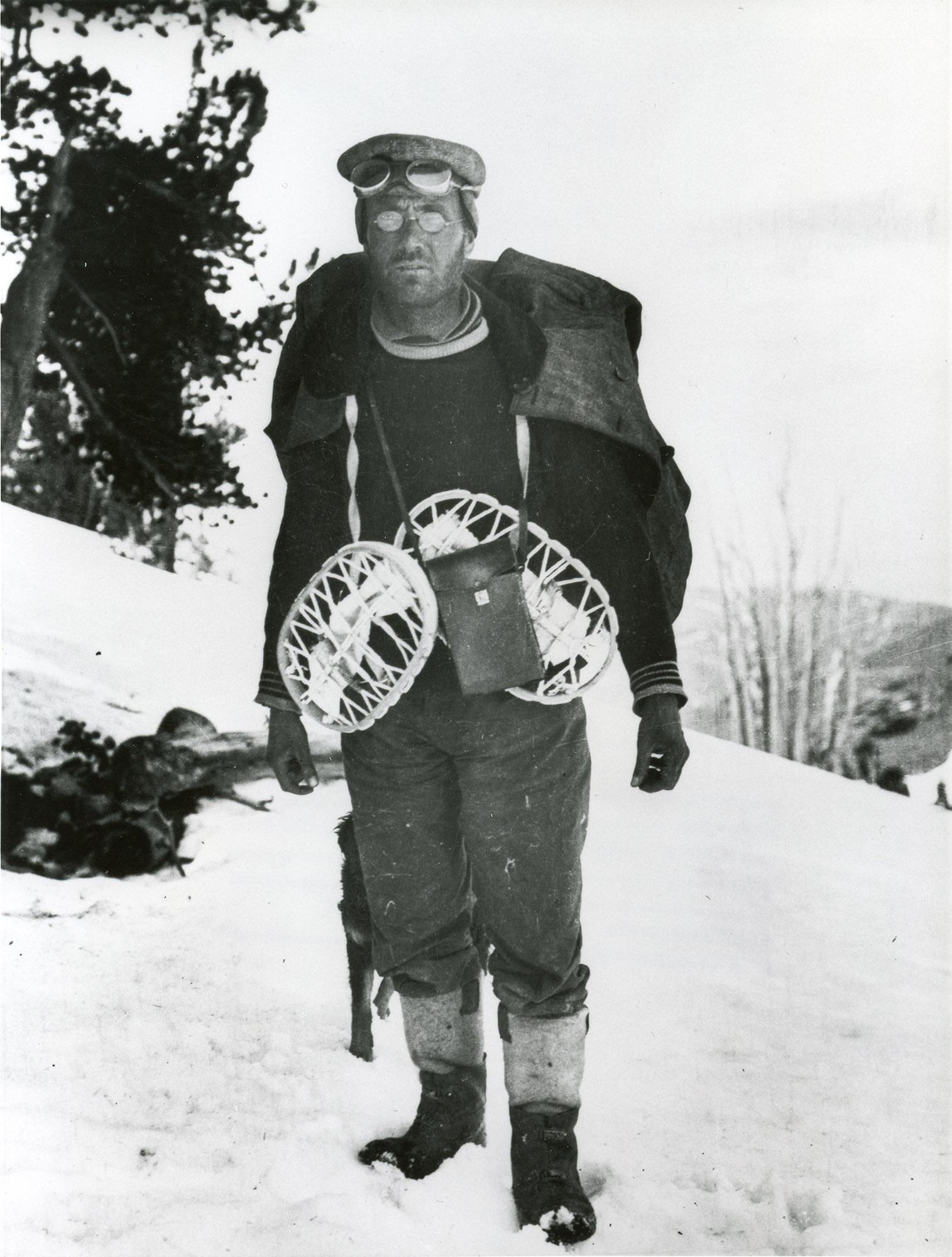 Professor James E. Church wearing goggles and snowshoes, standing on a snowy hillside